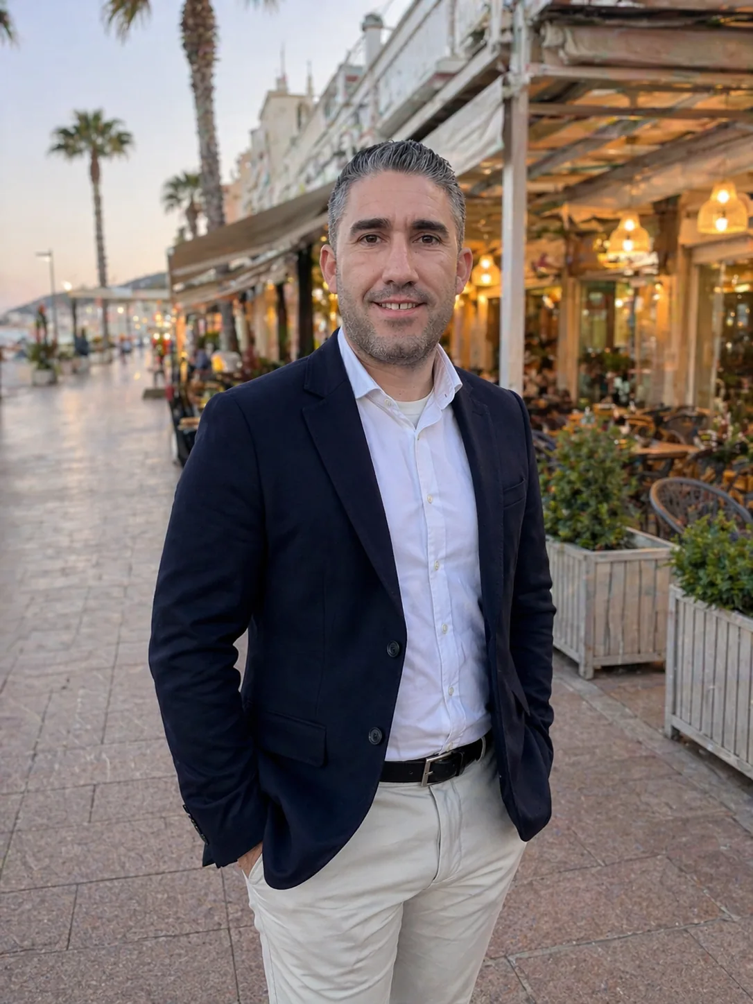 Juan, fundador de Gestiona Tu Futuro, en un paseo marítimo junto a terrazas de restaurantes al atardecer